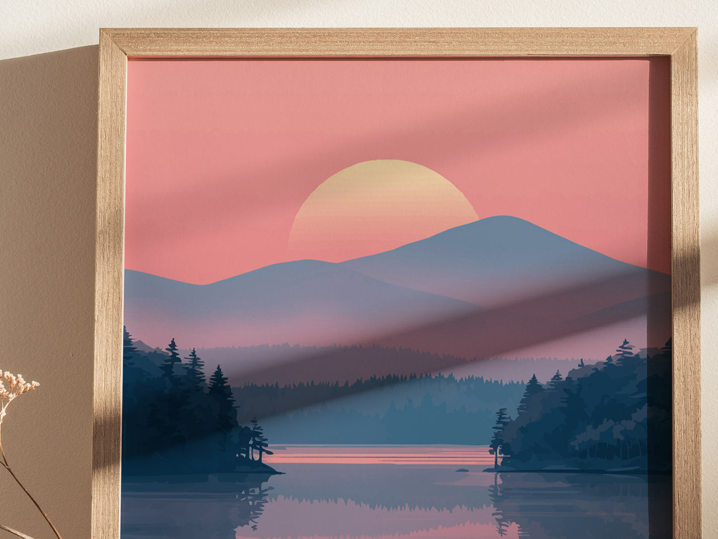 A framed poster depicts a serene landscape with a sunset over distant mountains, a lake, and silhouetted pine trees, set against a soft pink sky.