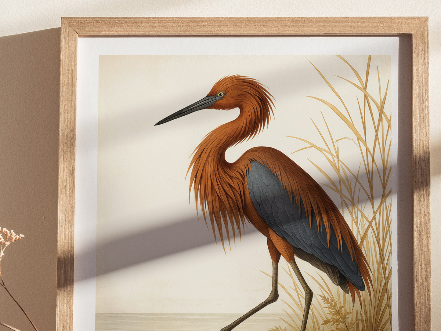 A framed poster depicting a Reddish Egret with shaggy rust-colored plumage and deep slate-blue wings stands elegantly against a backdrop of golden reeds. This wall art captures the birds unique beauty and grace.