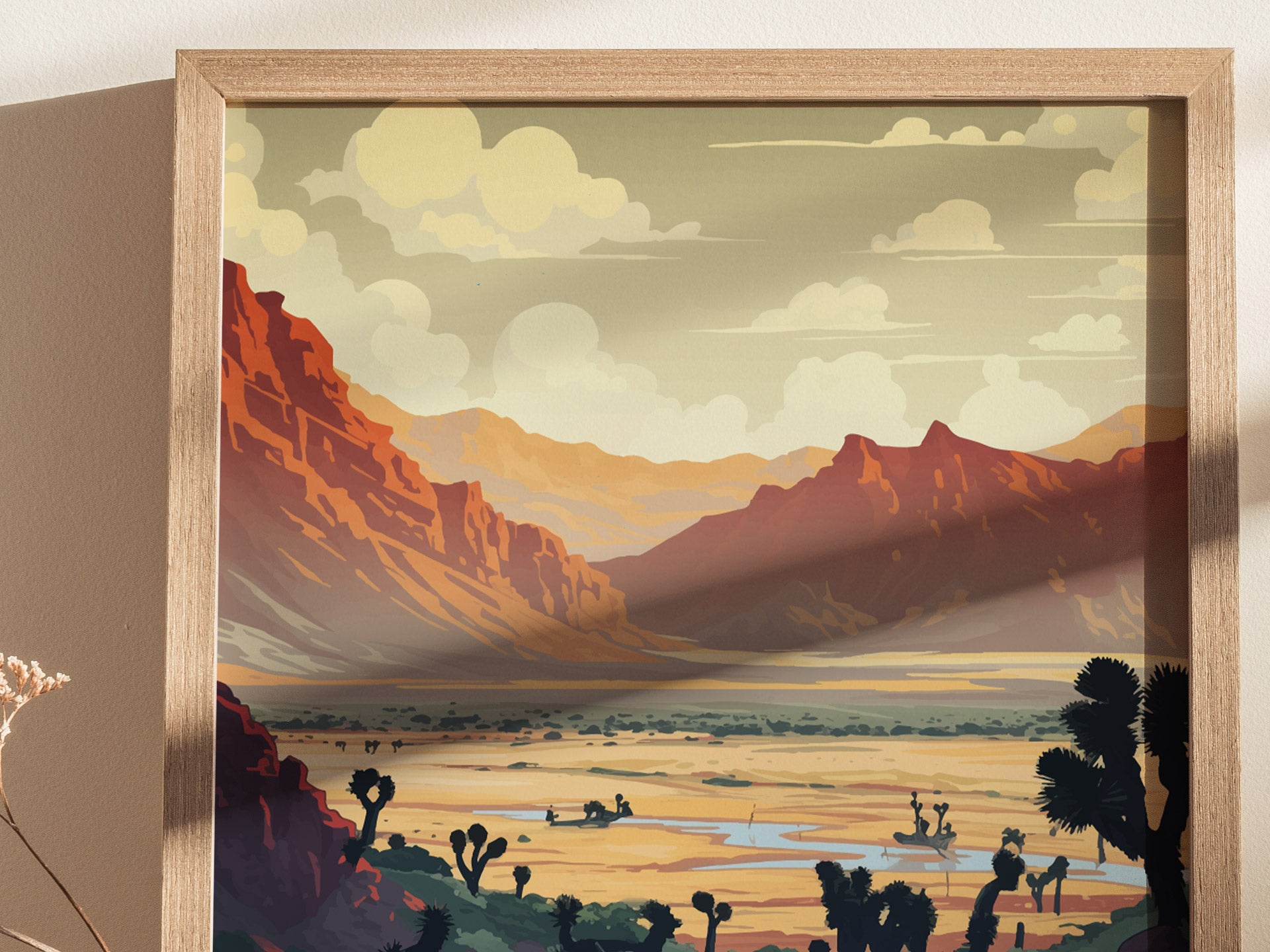 A framed art print depicts a desert landscape with red rocky mountains, scattered vegetation, and a cloudy sky. The scene captures a serene, expansive view of the terrain.