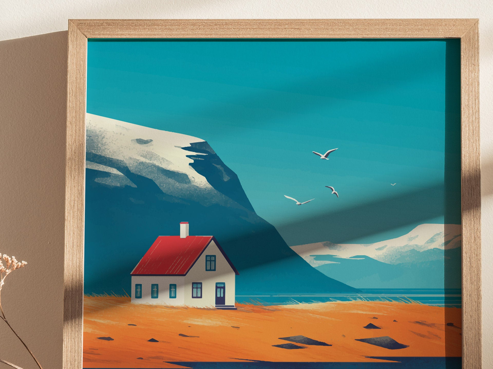 A framed poster depicts a stylized landscape with a small house with a red roof, surrounded by orange fields, mountains, and flying birds under a blue sky.