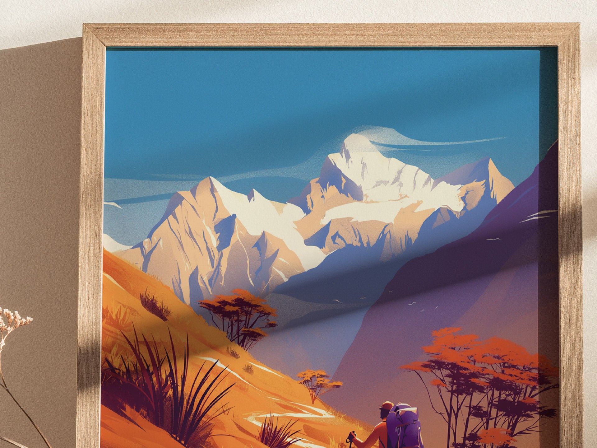 A framed poster depicts hikers on a vibrant trail with snow-capped mountains and colorful foliage under a clear blue sky, capturing the essence of an adventurous trek.