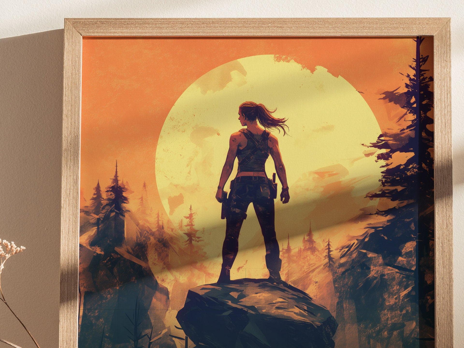A framed poster features a silhouette of a person standing on a rock against a large, vibrant orange sun and a forest backdrop, creating a dramatic, atmospheric scene.