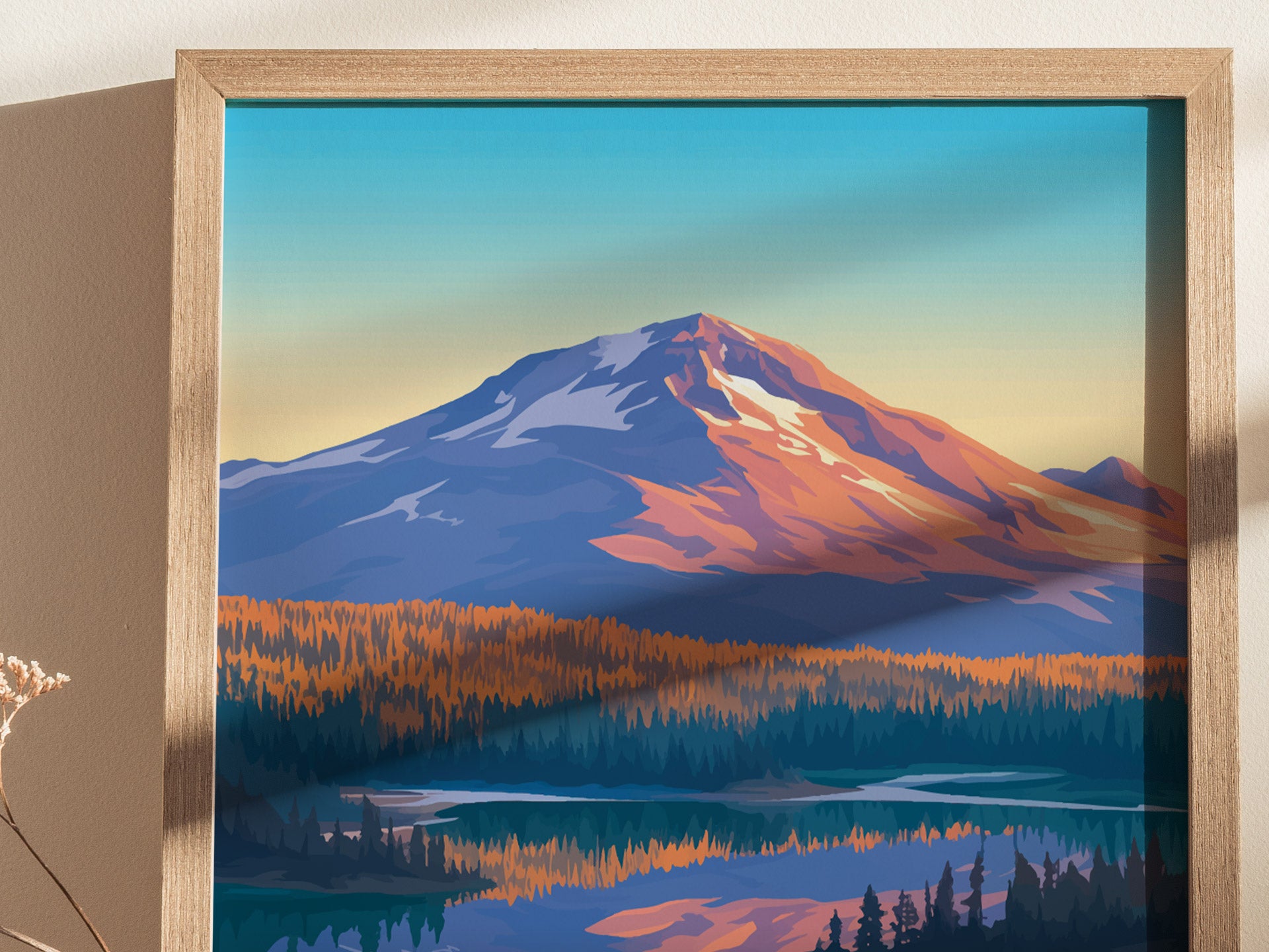 A framed poster depicts a stylized mountain landscape with a snow-capped peak and a forest below, set against a gradient sky. Brown frame and dried flowers are visible.