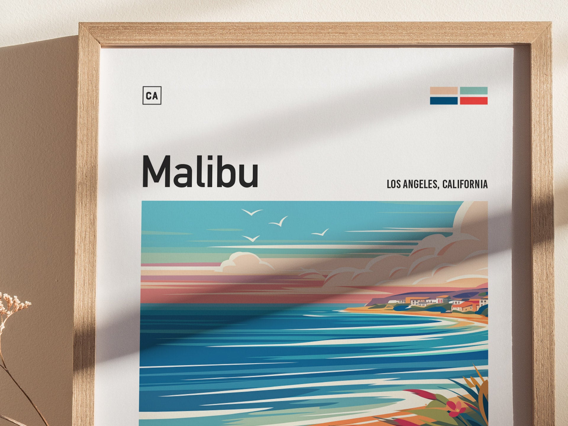 A framed poster featuring an abstract depiction of Malibus coastline with vibrant colors, ocean waves, and birds in the sky. The text reads Malibu, Los Angeles, California.