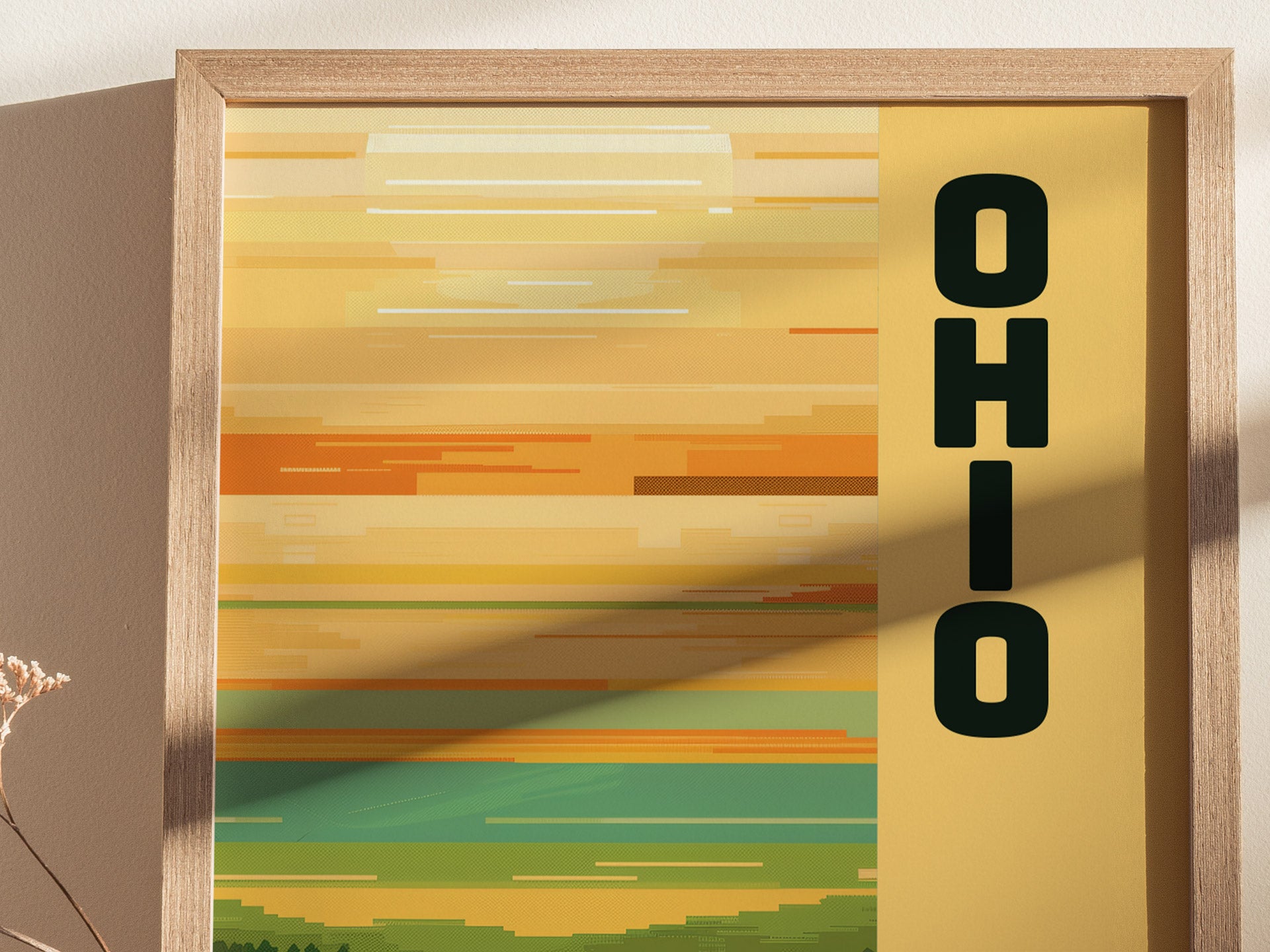 A framed poster with horizontal, minimalist stripes in warm yellow and orange hues features the word OHIO vertically on the right. Soft shadows add depth to the composition.