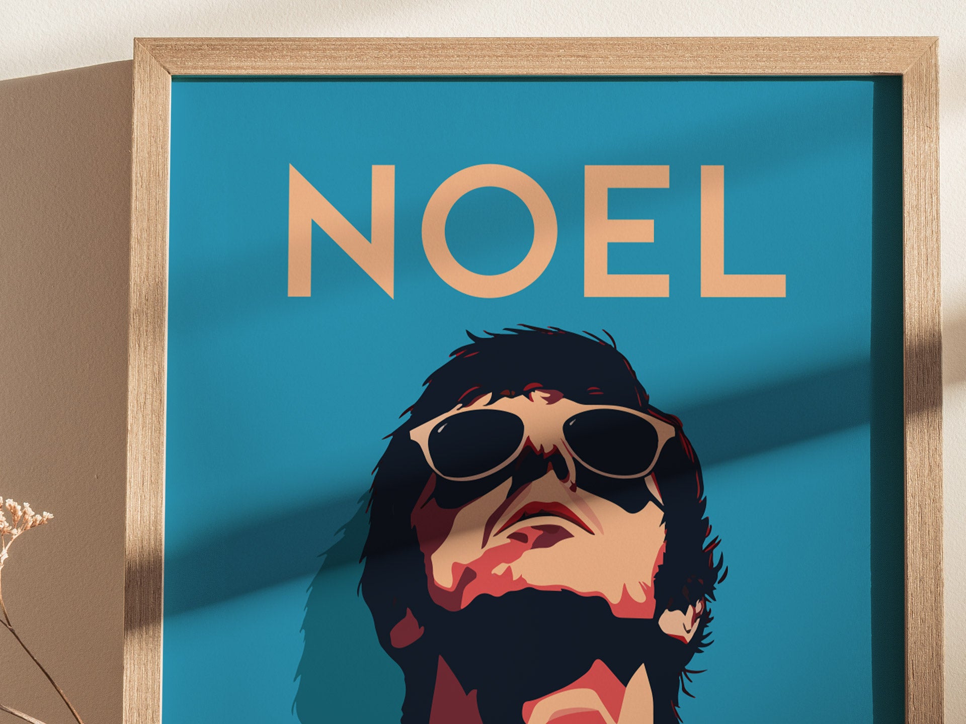 A stylized poster featuring a portrait of a person wearing sunglasses with the word NOEL above, set against a blue background in a wooden frame.