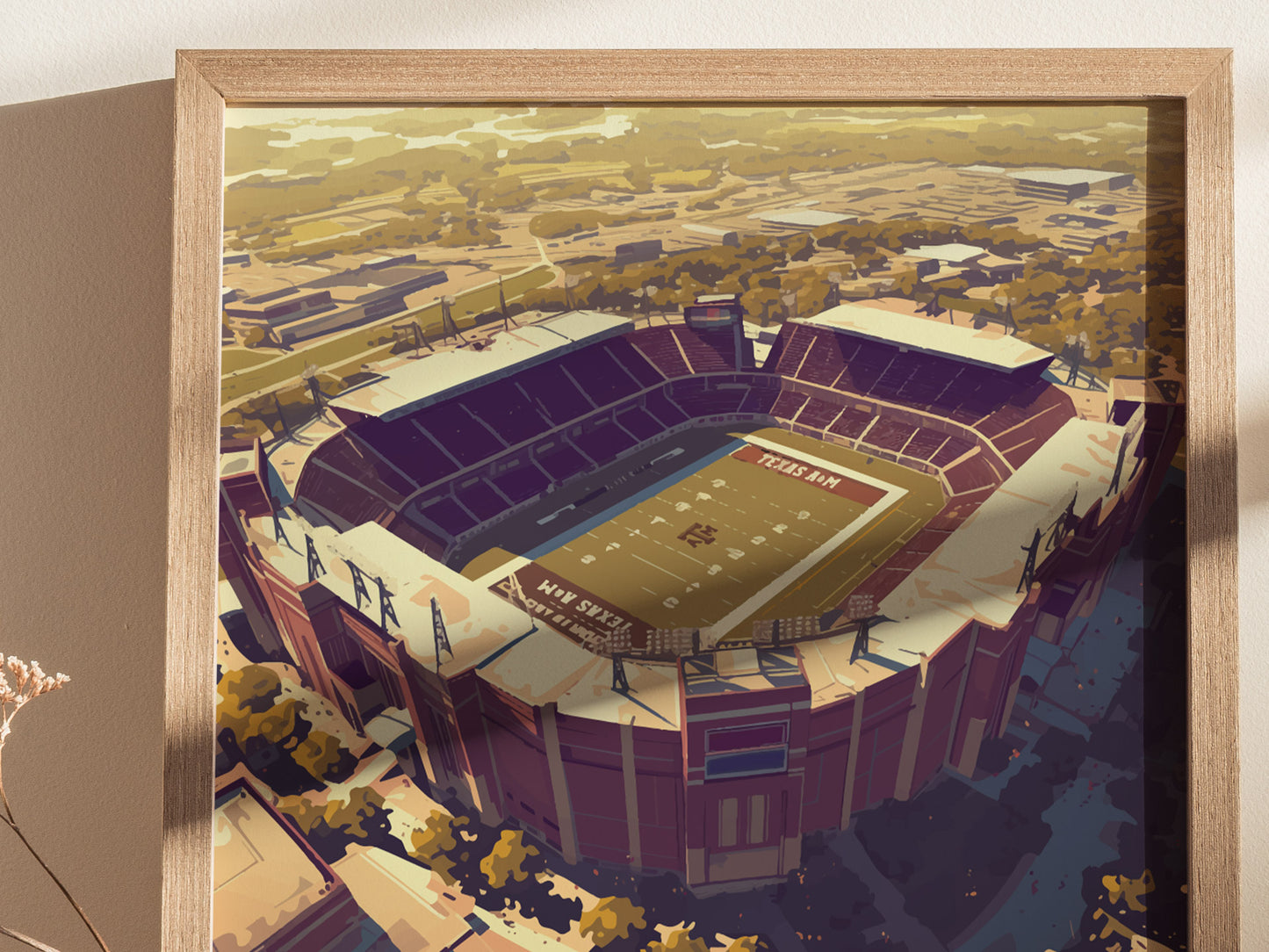 A framed artwork of Kyle Field, Texas A&Ms iconic stadium, showcasing its vast seating and field from an aerial perspective, with surrounding landscape details.