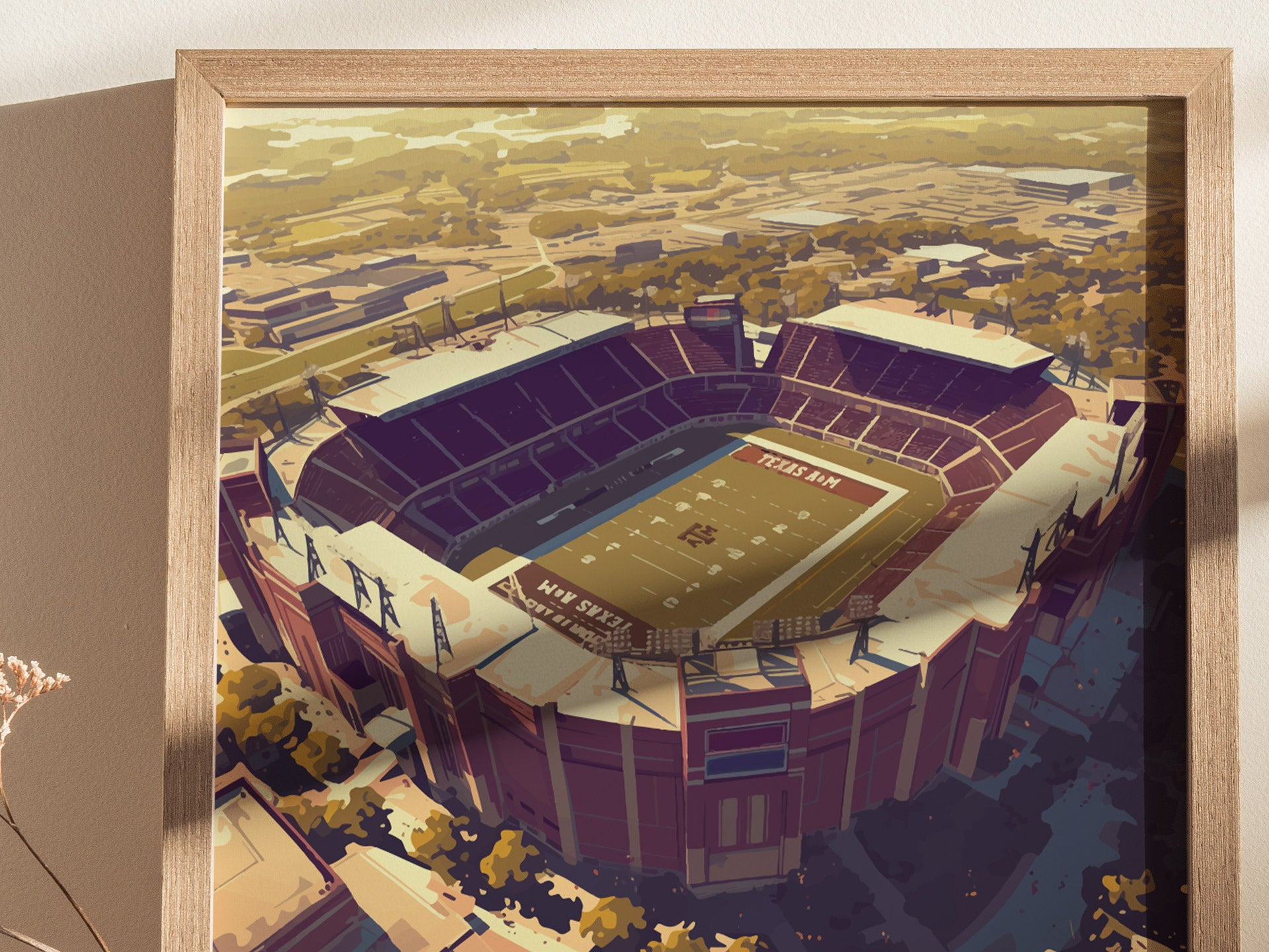 A framed artwork of Kyle Field, Texas A&Ms iconic stadium, showcasing its vast seating and field from an aerial perspective, with surrounding landscape details.