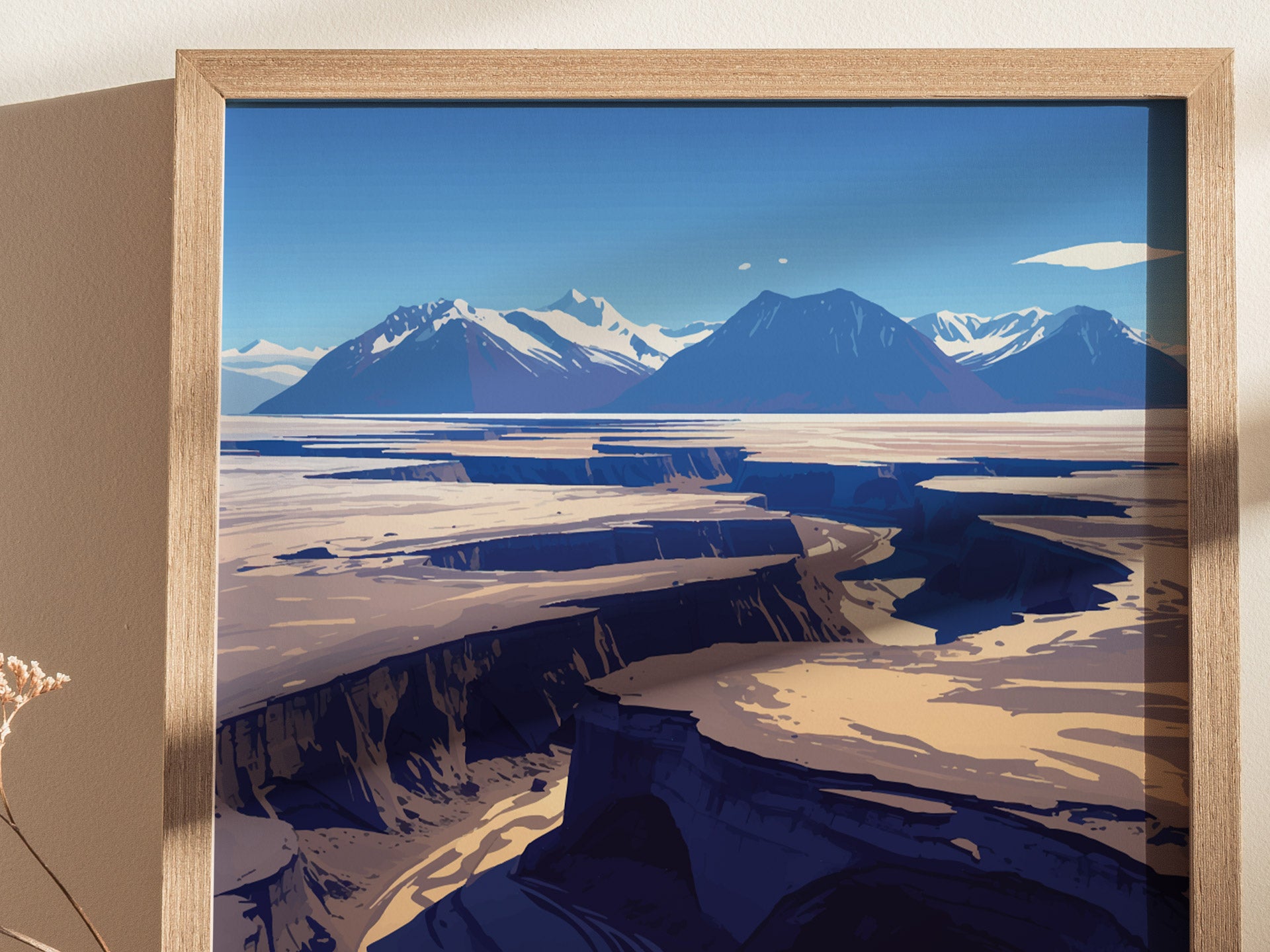 Framed artwork depicting a dramatic volcanic landscape with deep valleys and snow-capped mountains under a clear blue sky. The image captures the stark beauty of a remote wilderness.