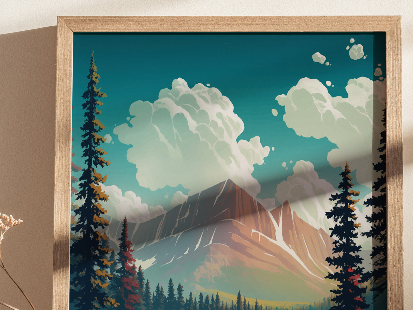 A framed art print depicts a scenic view of a mountain range with towering pine trees and fluffy clouds against a blue sky. The artwork is in a wooden frame.