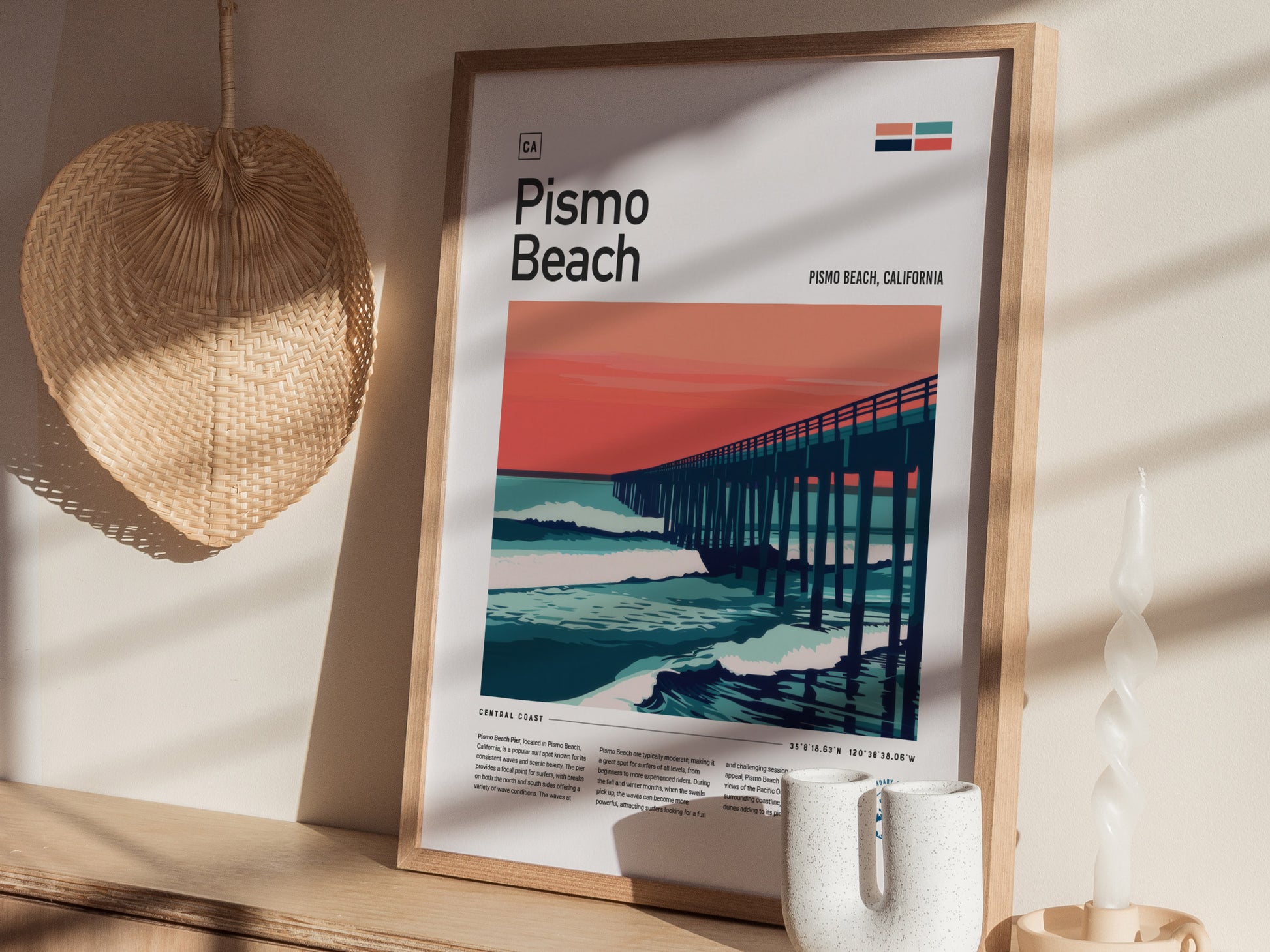 A framed Pismo Beach poster depicting a pier against a vibrant sunset is displayed on a wooden shelf, accompanied by a woven basket and a white twisted candle.