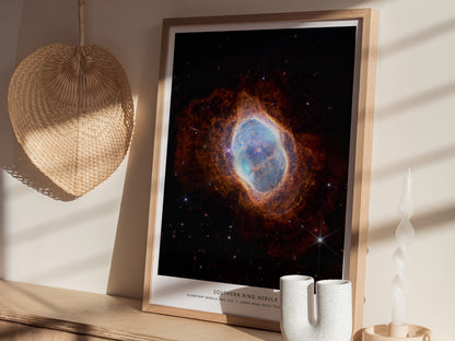 Natural wood framed Southern Ring Nebula space print leaning on a shelf beside plants and neutral accessories