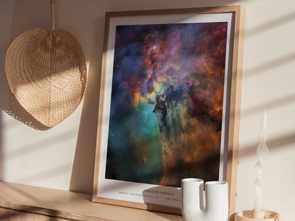 A beautifully framed poster titled Lagoon Nebula features a vivid cosmic scene with swirling colors of blue, orange, and purple, depicting a nebula filled with stars and gas clouds.