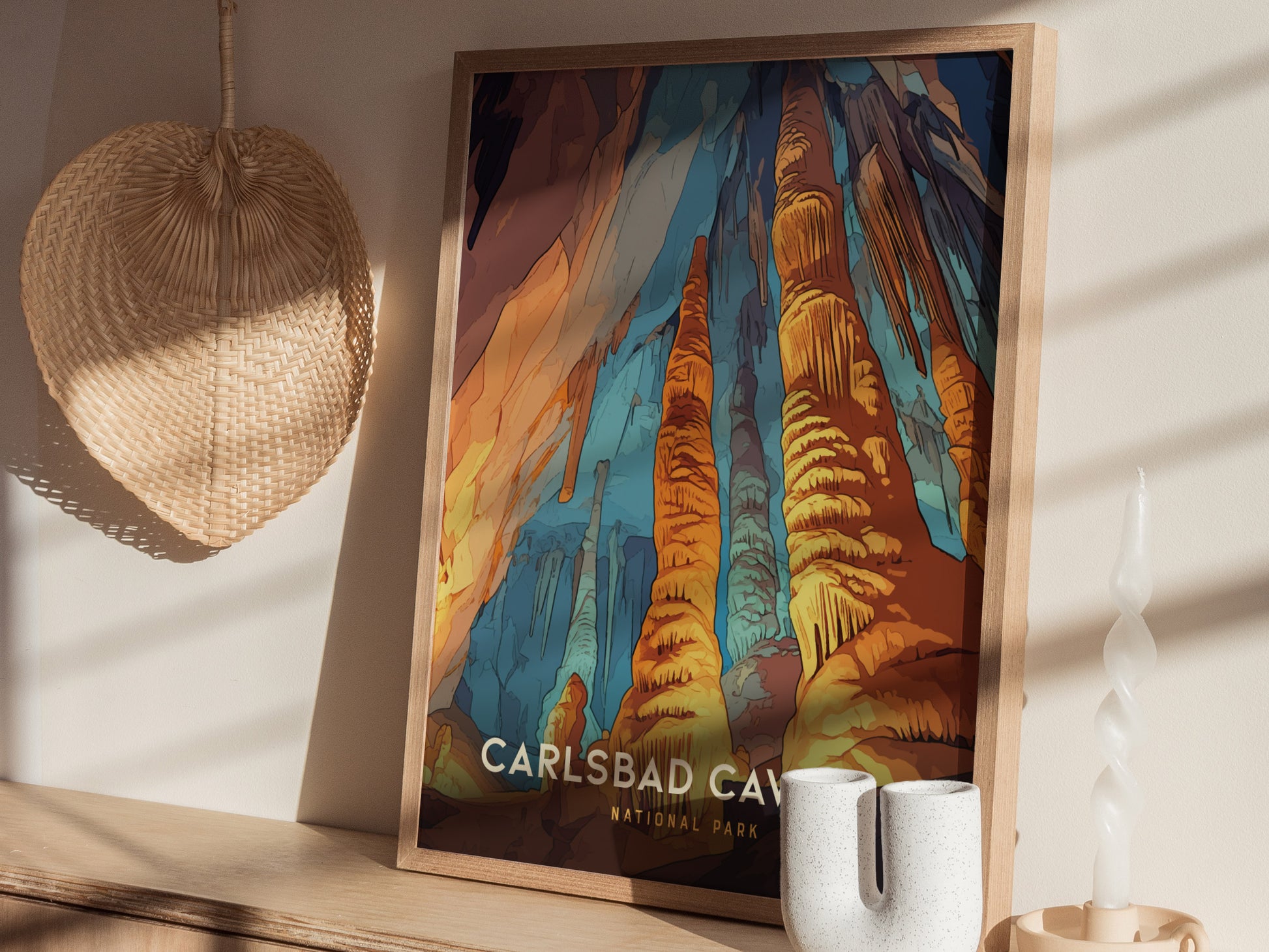 A framed Carlsbad Caverns National Park poster featuring vibrant rock formations is displayed on a wooden shelf. A woven fan and decorative candle are nearby, adding to the aesthetic.
