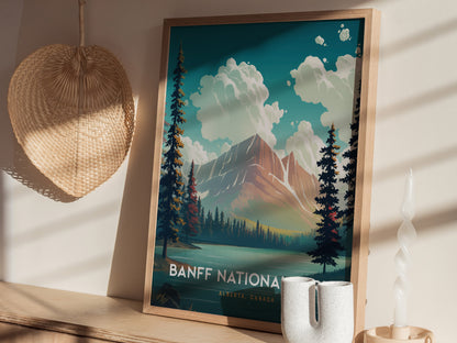 A framed Banff National Park poster shows a vibrant landscape with mountains, trees, and clouds. It sits on a wooden shelf beside a woven basket and a twisted candle.