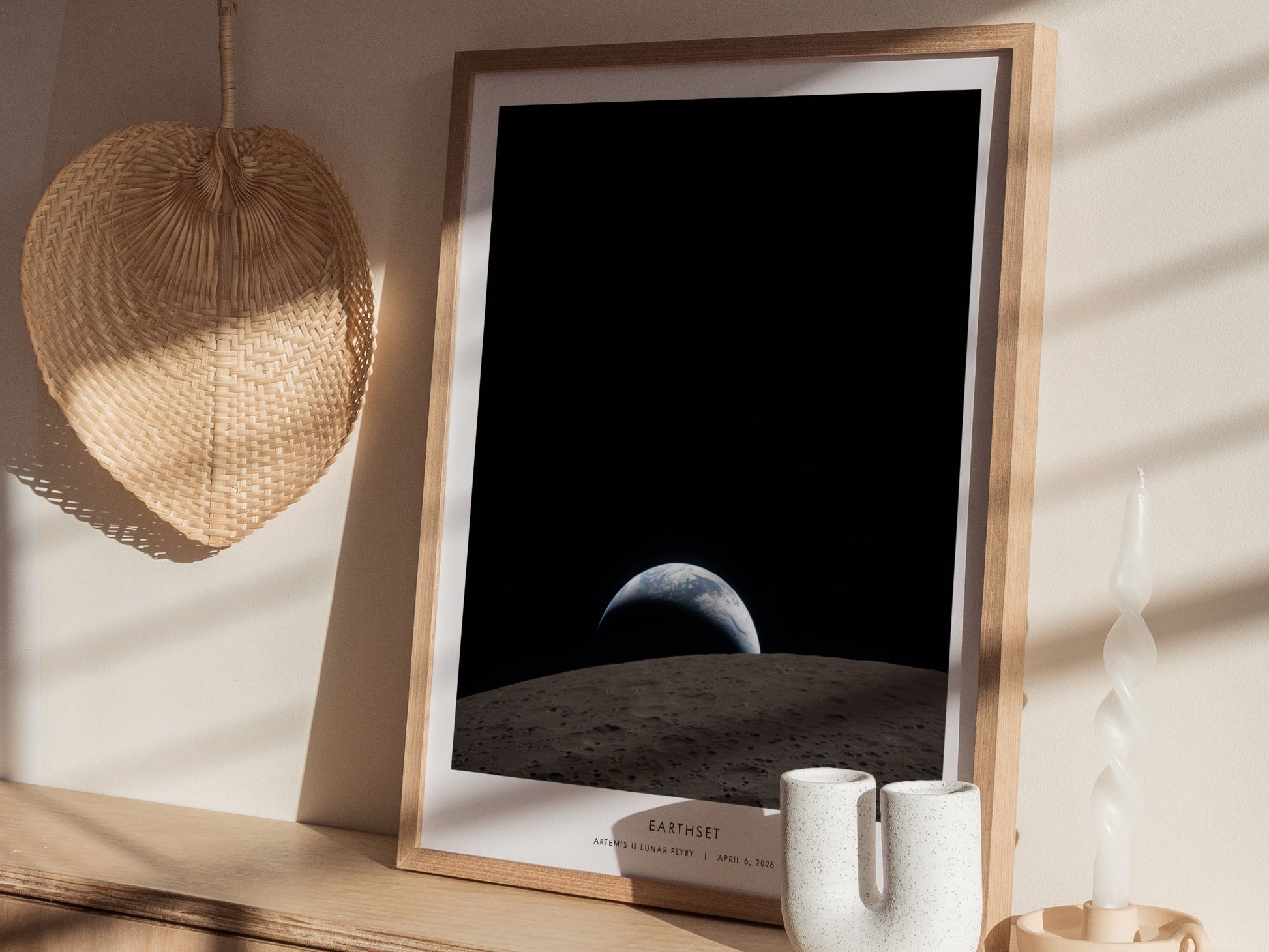 A framed poster titled Earthset depicts a stunning view of Earth rising over the lunar surface, with a dark, starry background.