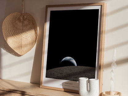 A framed poster titled Earthset depicts a stunning view of Earth rising over the lunar surface, with a dark, starry background.