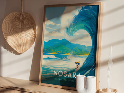 A framed poster of a surfer on a large wave with mountains in the background sits on a wooden shelf. A woven basket and twisted candle are nearby, casting shadows.