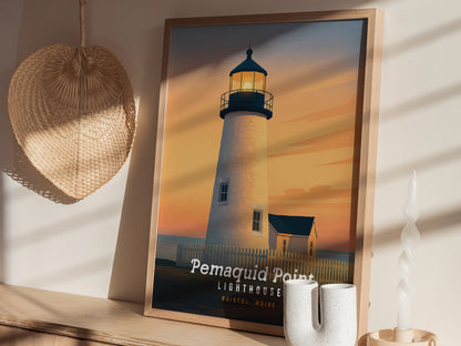 A framed art print of the Pemaquid Point Lighthouse in Bristol, Maine, is displayed on a wall. The artwork features a serene sunset with warm hues illuminating the lighthouse and surrounding landscape, creating a tranquil coastal scene.