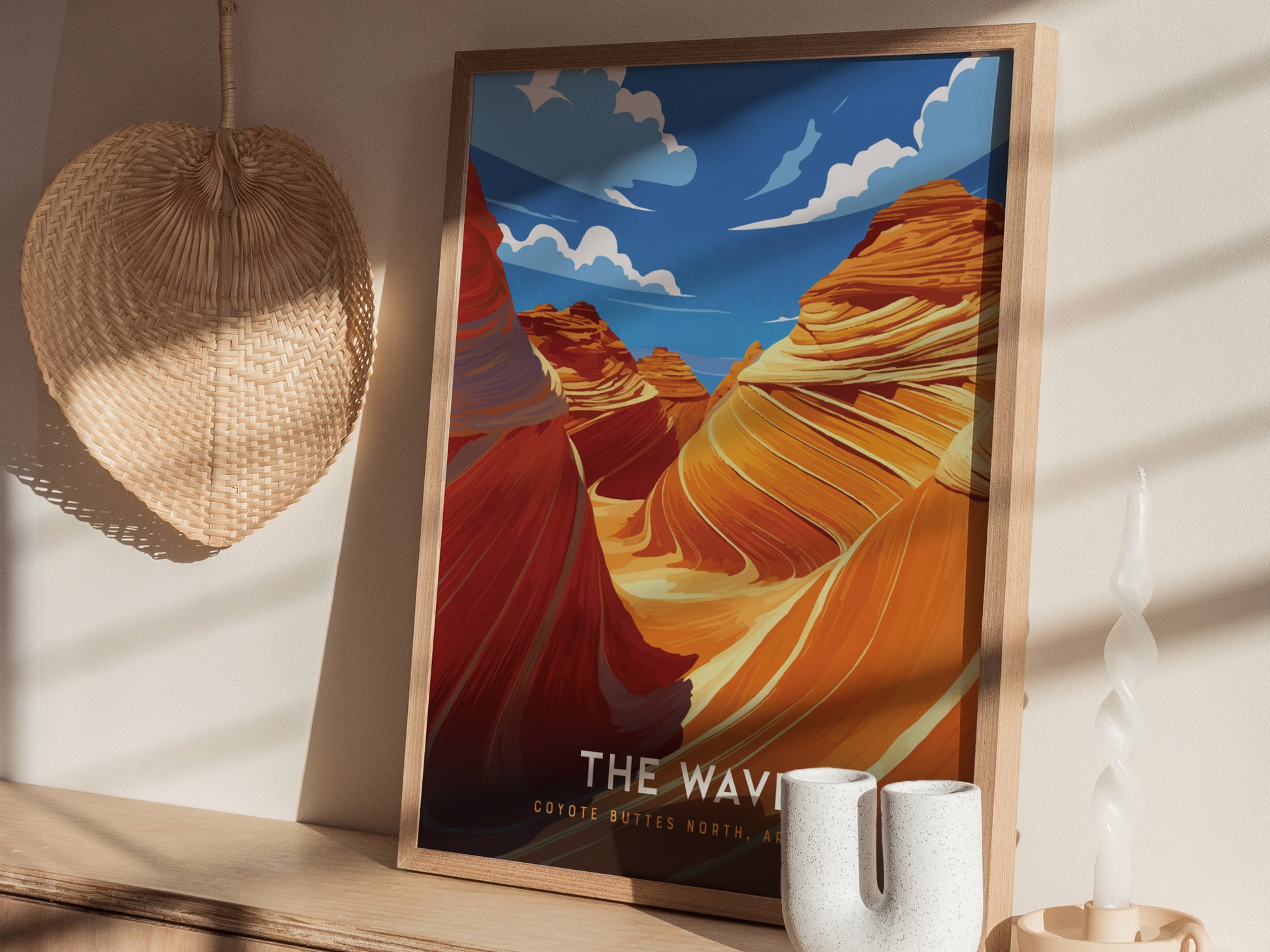 A framed poster of The Wave in Coyote Buttes, Arizona, with vibrant swirling sandstone formations. It rests on a wooden shelf beside a decorative basket and twisted white candle.