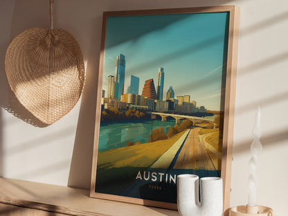 A framed Austin, Texas skyline poster sits on a wooden shelf with a woven wall decoration and a modern ceramic candle holder nearby, illuminated by soft sunlight.