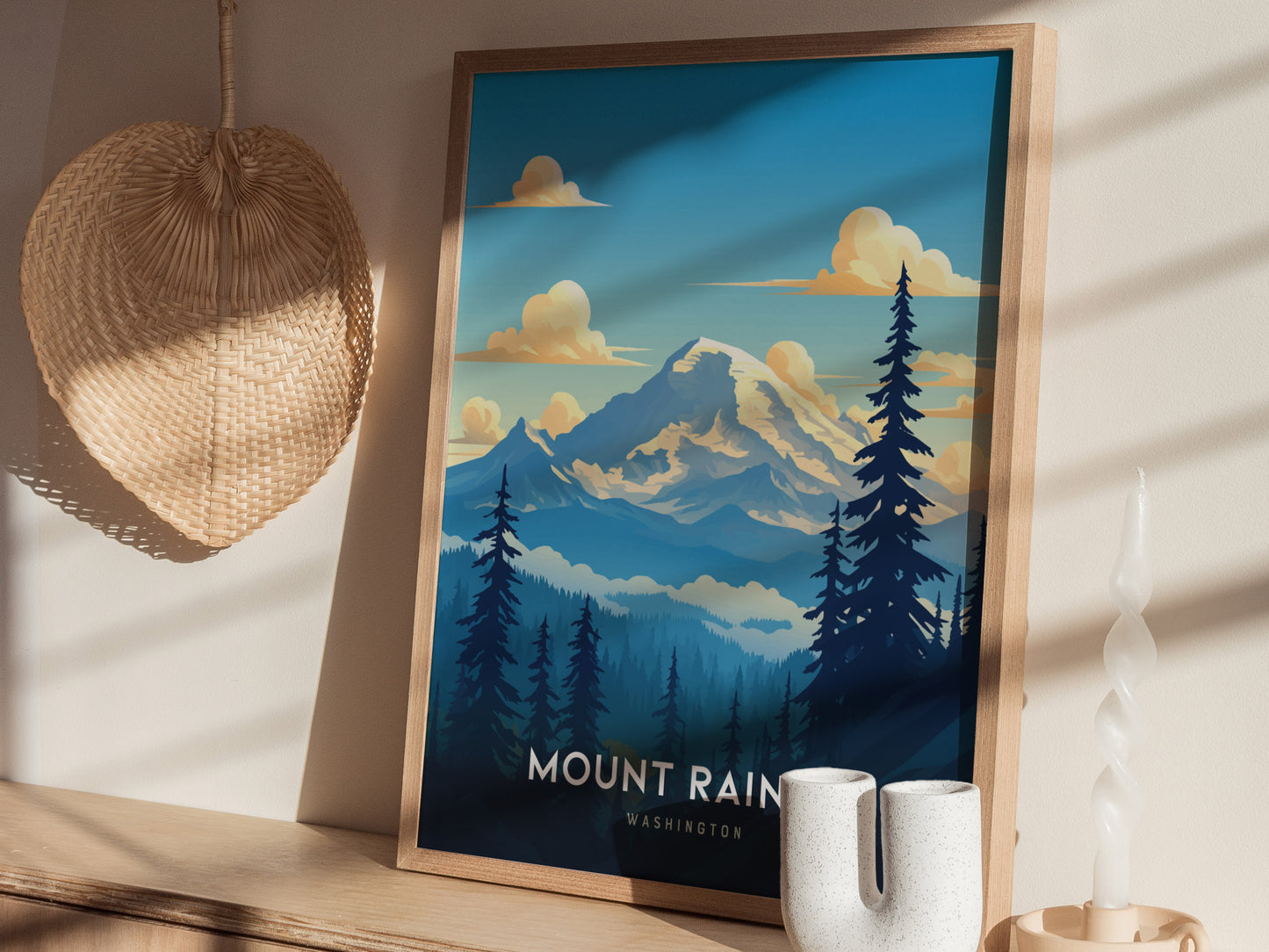 A framed Mount Rainier poster rests on a wooden shelf, surrounded by a wicker basket and a twisted white candle. Sunlight casts shadows on the wall.