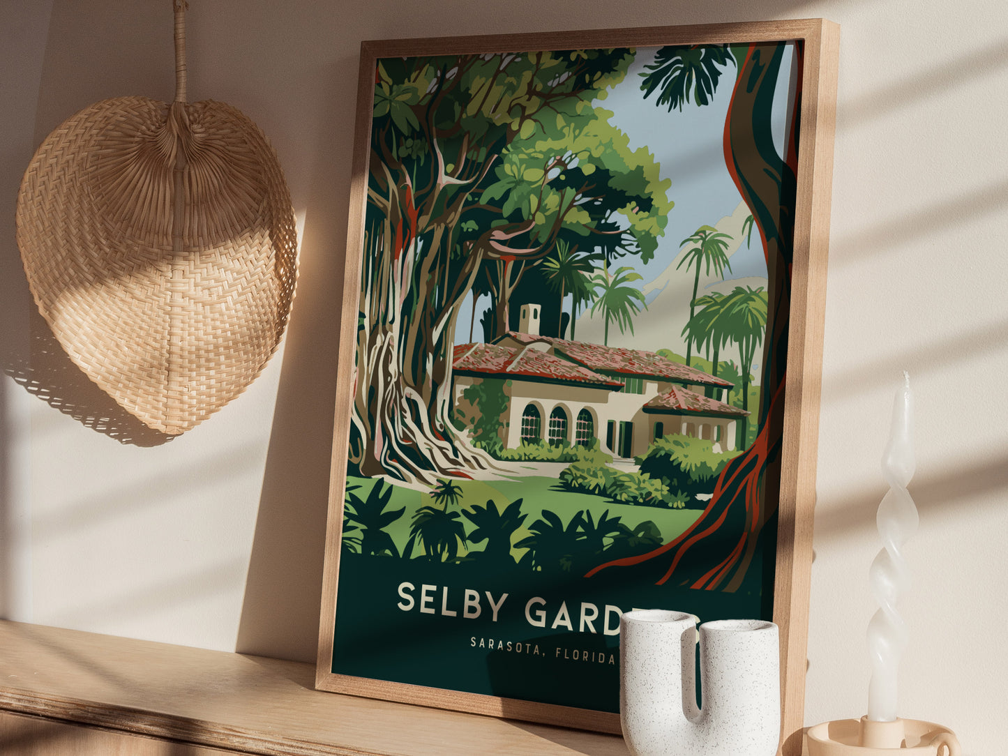 A framed poster of Selby Gardens in Sarasota, Florida, depicts lush greenery and a charming building. Its displayed on a wooden shelf with decorative items, including a woven fan and.