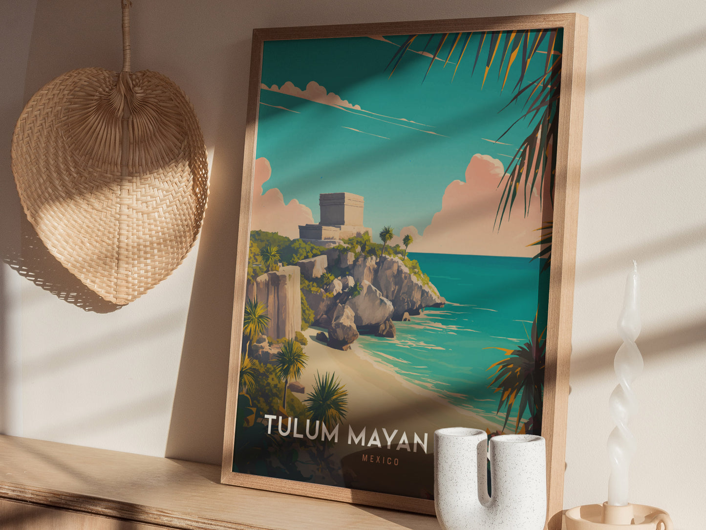 A framed poster of Tulum Mayan Ruins is displayed on a wooden shelf, alongside a woven basket and ceramic decor. Sunlight casts shadows across the scene.
