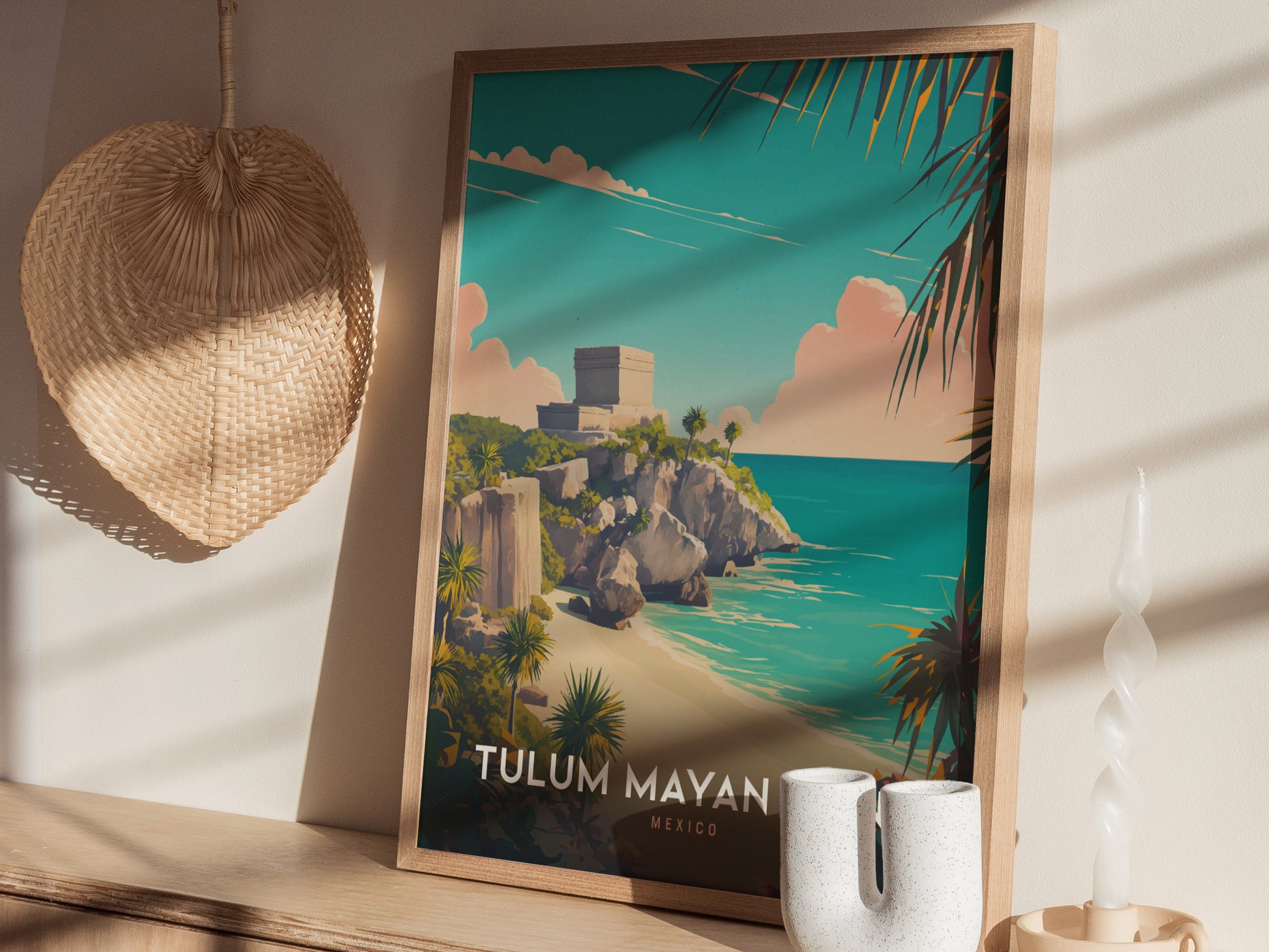 A framed poster of Tulum Mayan Ruins is displayed on a wooden shelf, alongside a woven basket and ceramic decor. Sunlight casts shadows across the scene.