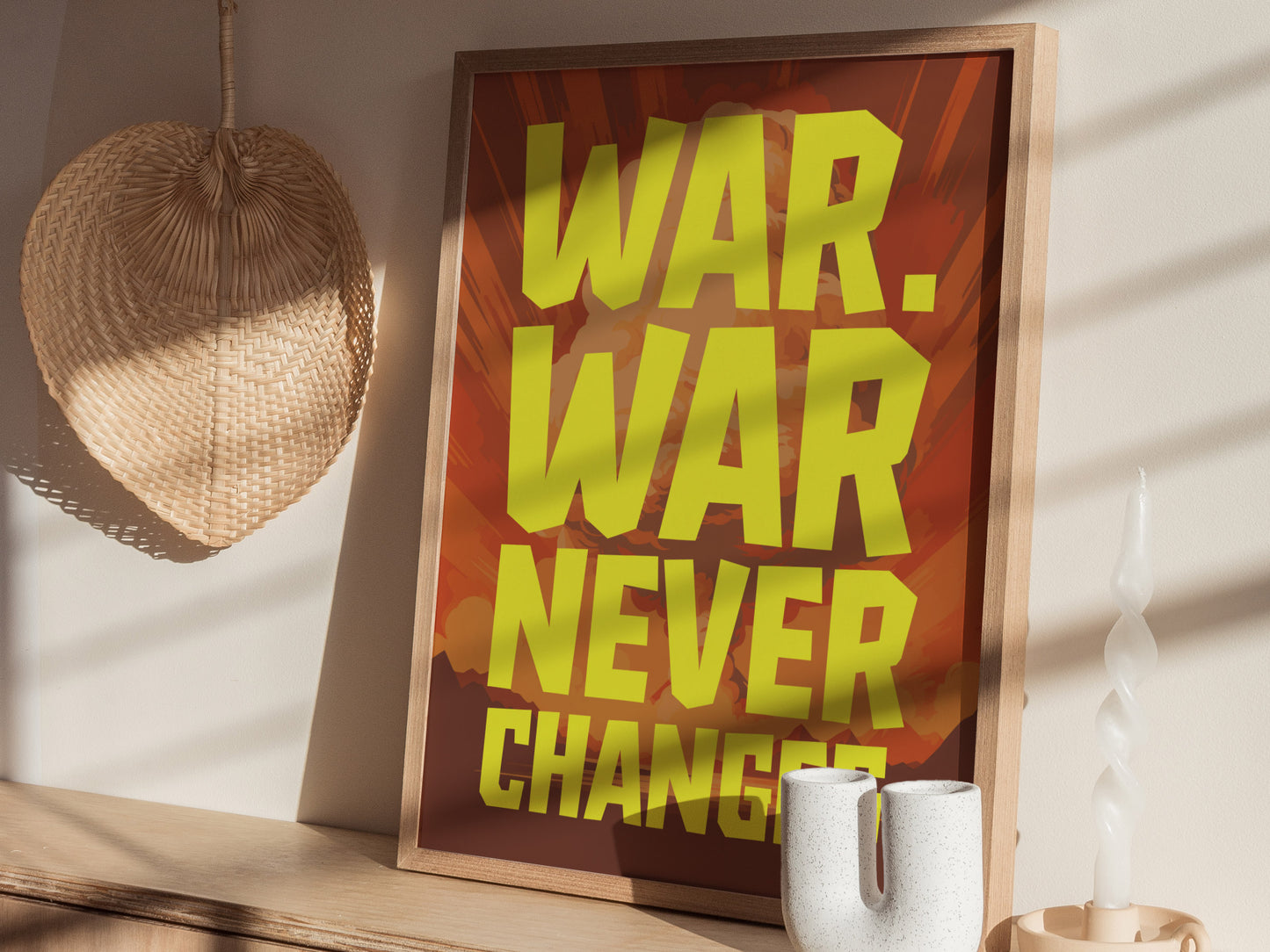 Framed poster with bold yellow text WAR. WAR NEVER CHANGES against a reddish background, displayed on a wooden surface with a woven wall decor and twisted candle nearby.