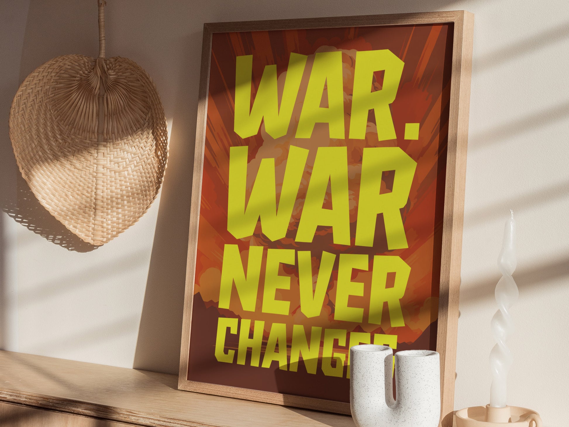 Framed poster with bold yellow text WAR. WAR NEVER CHANGES against a reddish background, displayed on a wooden surface with a woven wall decor and twisted candle nearby.