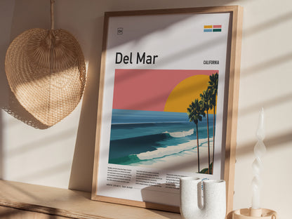 A framed poster titled Del Mar showcases a vibrant California sunset with a large yellow sun setting behind stylized palm trees and rolling ocean waves.