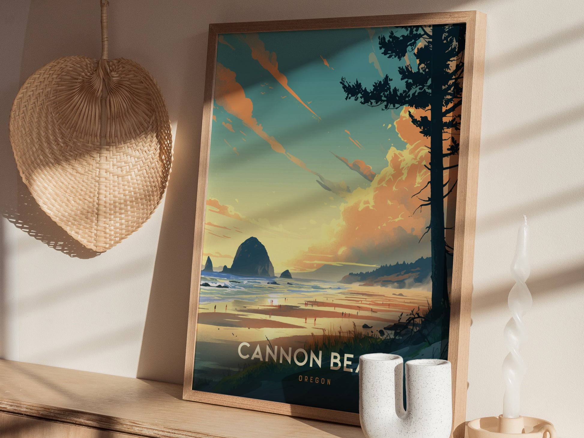 Framed poster of Cannon Beach, Oregon featuring Haystack Rock and a vibrant sunset, displayed on a shelf with a woven basket and decorative candle nearby.