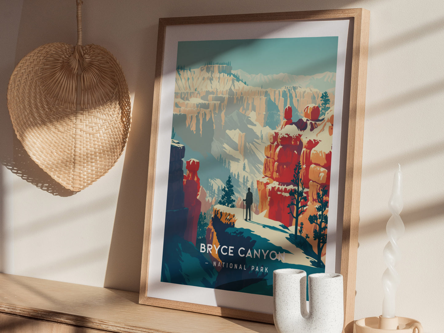 A framed Bryce Canyon National Park print is displayed on a wooden shelf, accompanied by a woven basket and a decorative candle. Sunlight casts shadows across the scene.