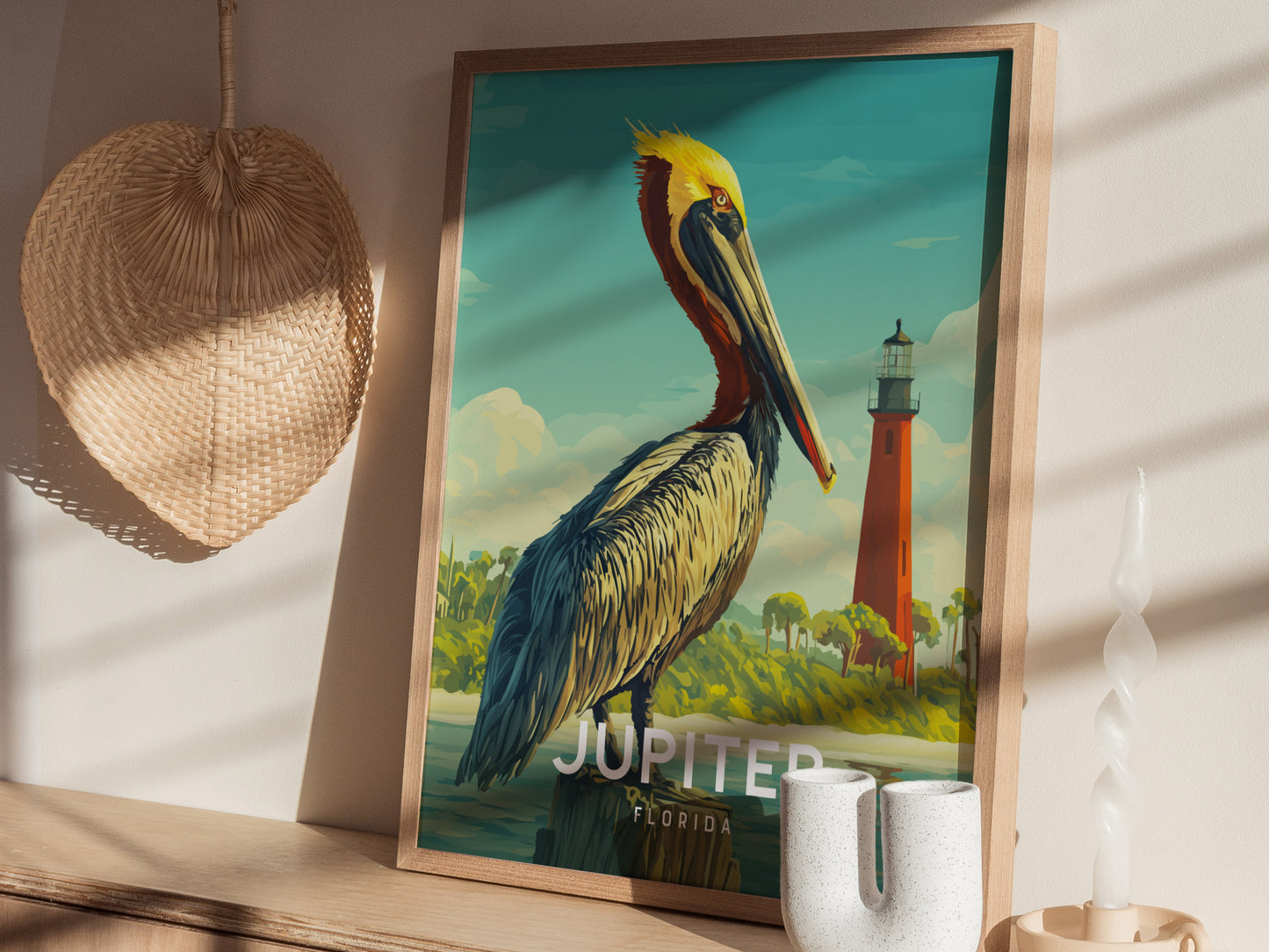 Framed artwork of a pelican with a lighthouse in the background, displayed on a wall.