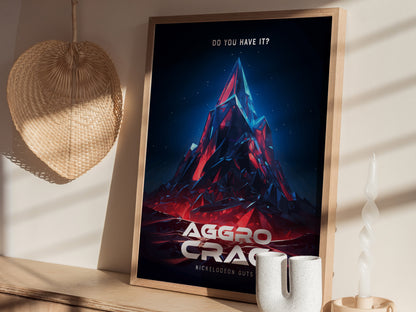 A framed Aggro Crag poster from Nickelodeon GUTS is displayed on a shelf with a woven wall decoration and a twist candle nearby. Sunlight casts shadows across the scene.
