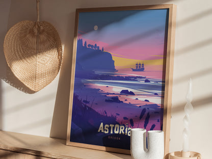 Framed poster of Astoria, Oregon, featuring a pirate ship at sunset with vibrant pink and blue tones. Displayed on a wooden shelf beside a woven hat and decorative objects.
