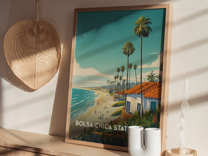 A framed Bolsa Chica State Beach poster rests on a wooden shelf, depicting a vibrant coastal scene with palm trees and ocean waves. A woven basket and candle are nearby.