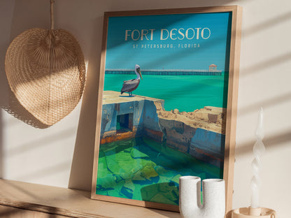 Framed poster featuring a pelican on fort ruins with turquoise water, labeled Fort Desoto, St Petersburg, Florida, displayed on a wooden shelf beside a woven basket and twisted candle.