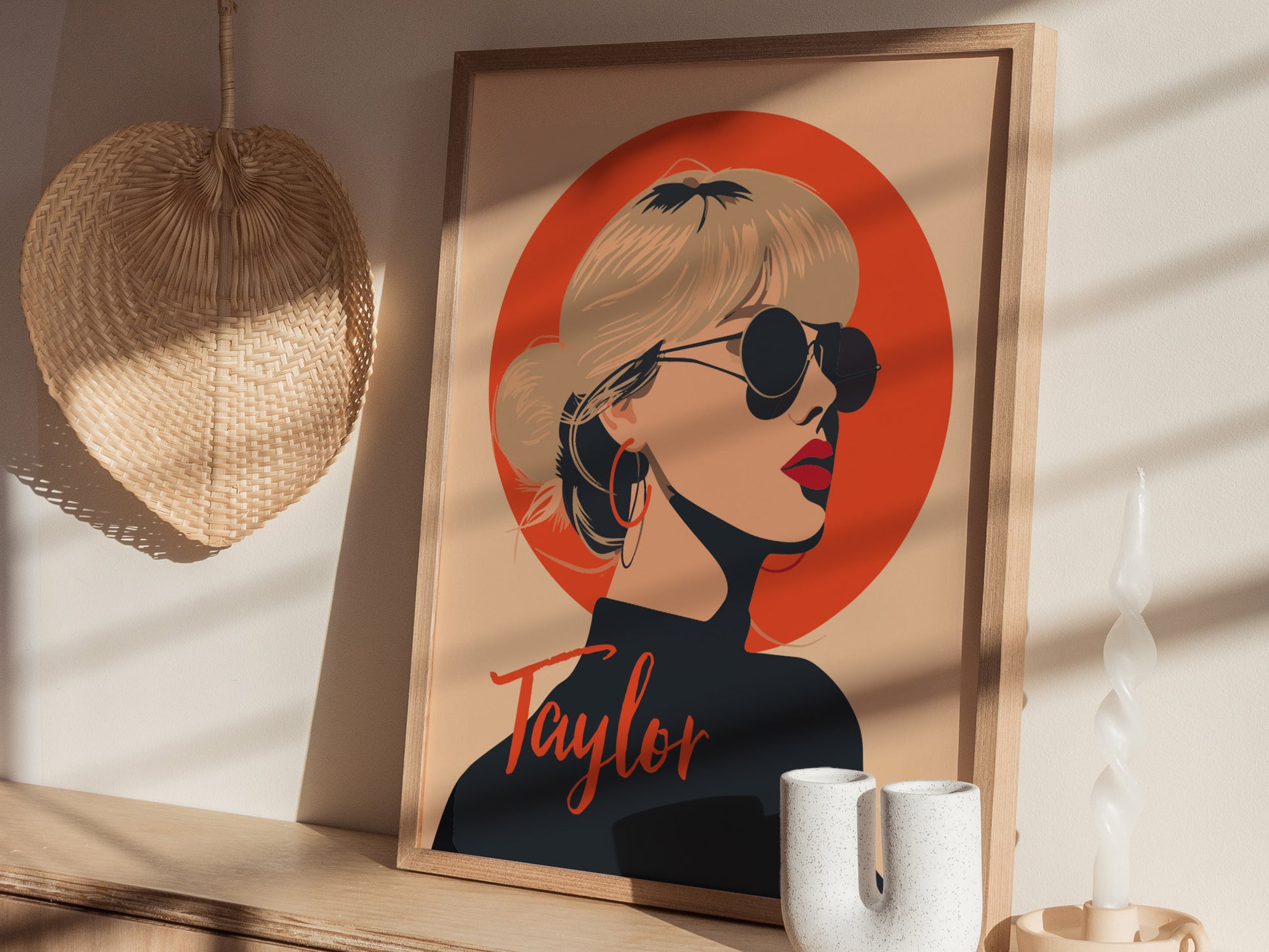 A framed poster featuring a minimalist illustration of a woman with sunglasses, set against an orange circle. It is displayed on a wooden shelf with decorative items nearby.