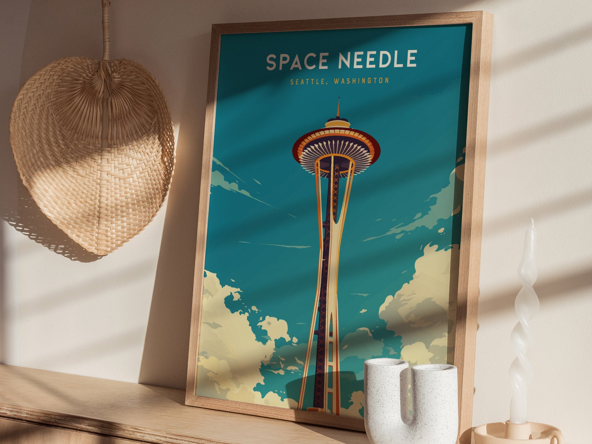 A framed Space Needle poster with a vintage style is displayed on a wooden shelf alongside a woven wall decoration and a unique candle holder.