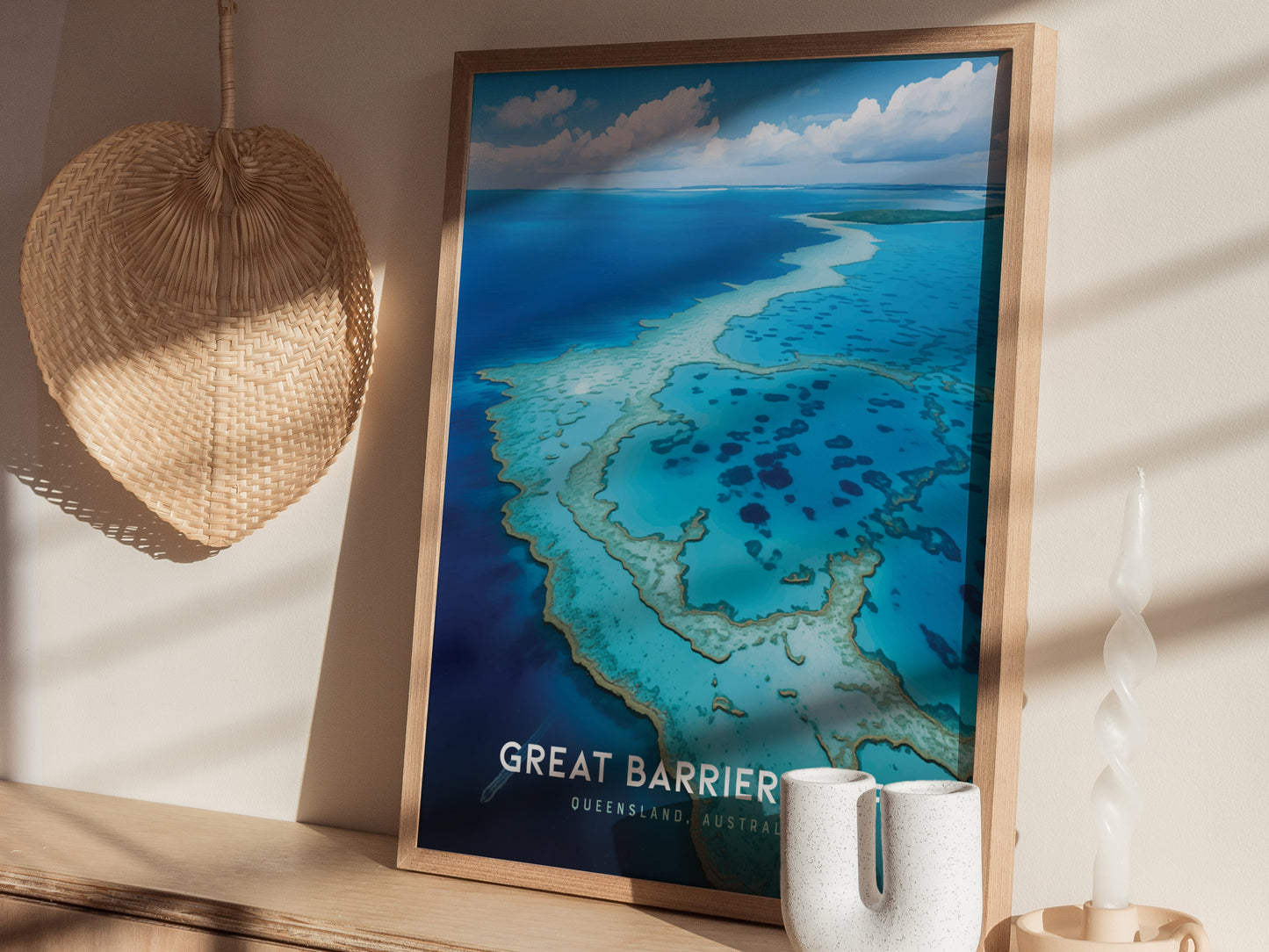 A framed poster of the Great Barrier Reef in vibrant blue hues is displayed on a shelf alongside a woven hat and decorative candle.