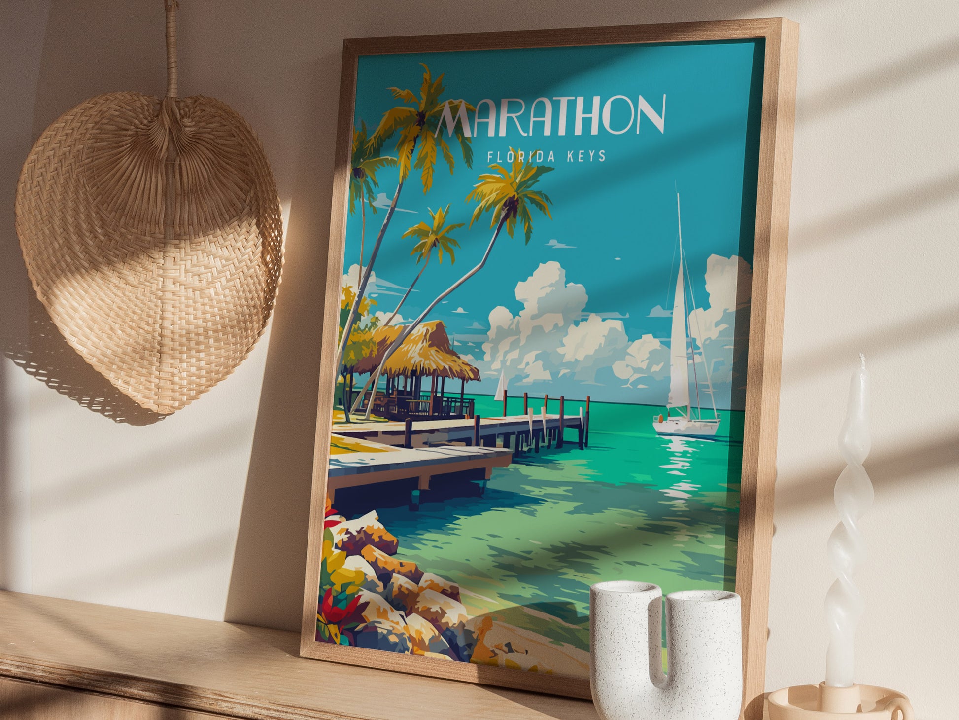 Framed Marathon Florida Keys poster featuring turquoise waters, palm trees, and a sailboat beside a rustic pier. Nearby, a woven wall decoration and modern decor elements complete the coastal scene.