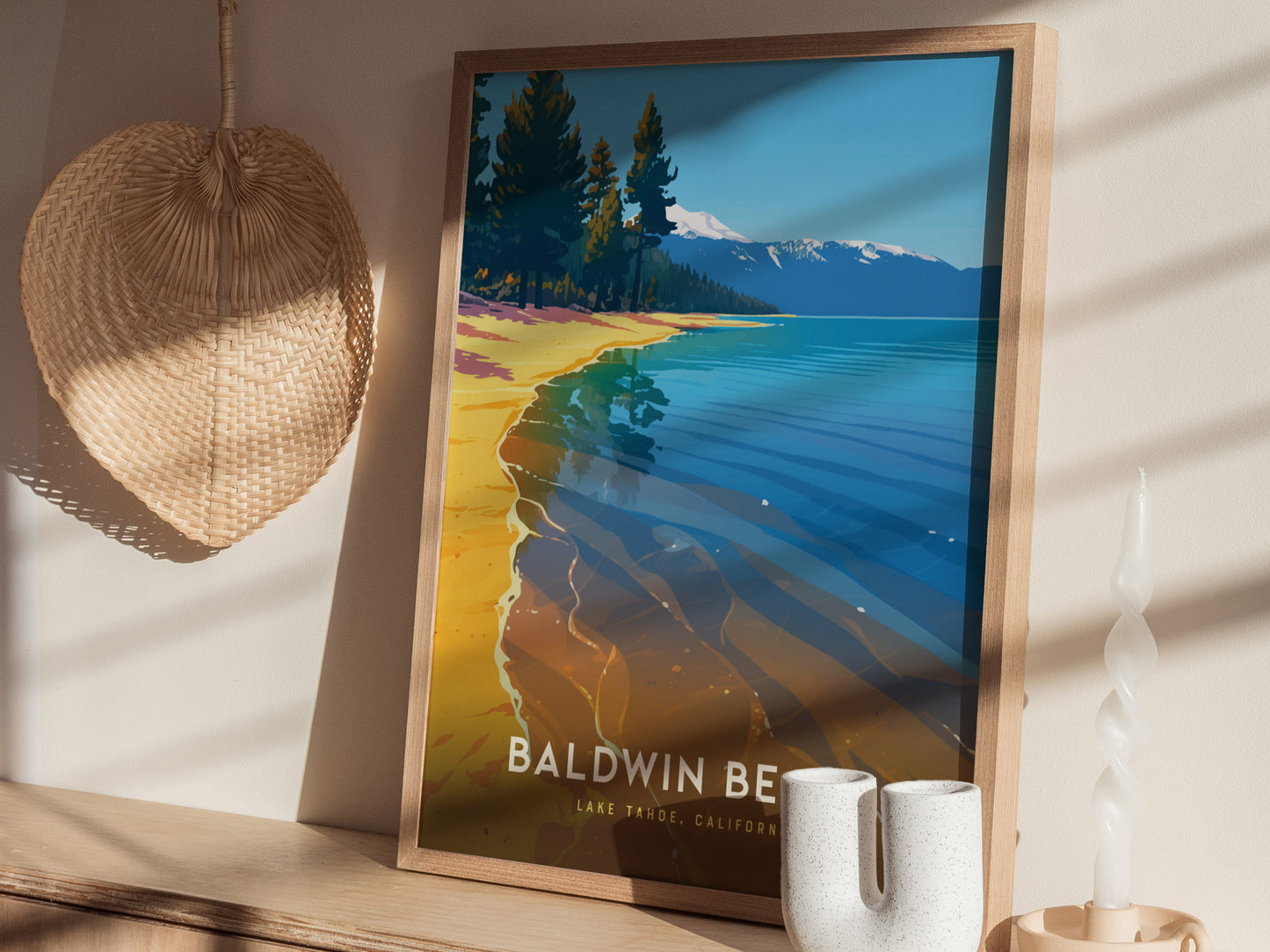 A framed poster of Baldwin Beach at Lake Tahoe, featuring clear blue waters and a tree-lined shore, is displayed on a wooden shelf next to a woven basket and decorative.