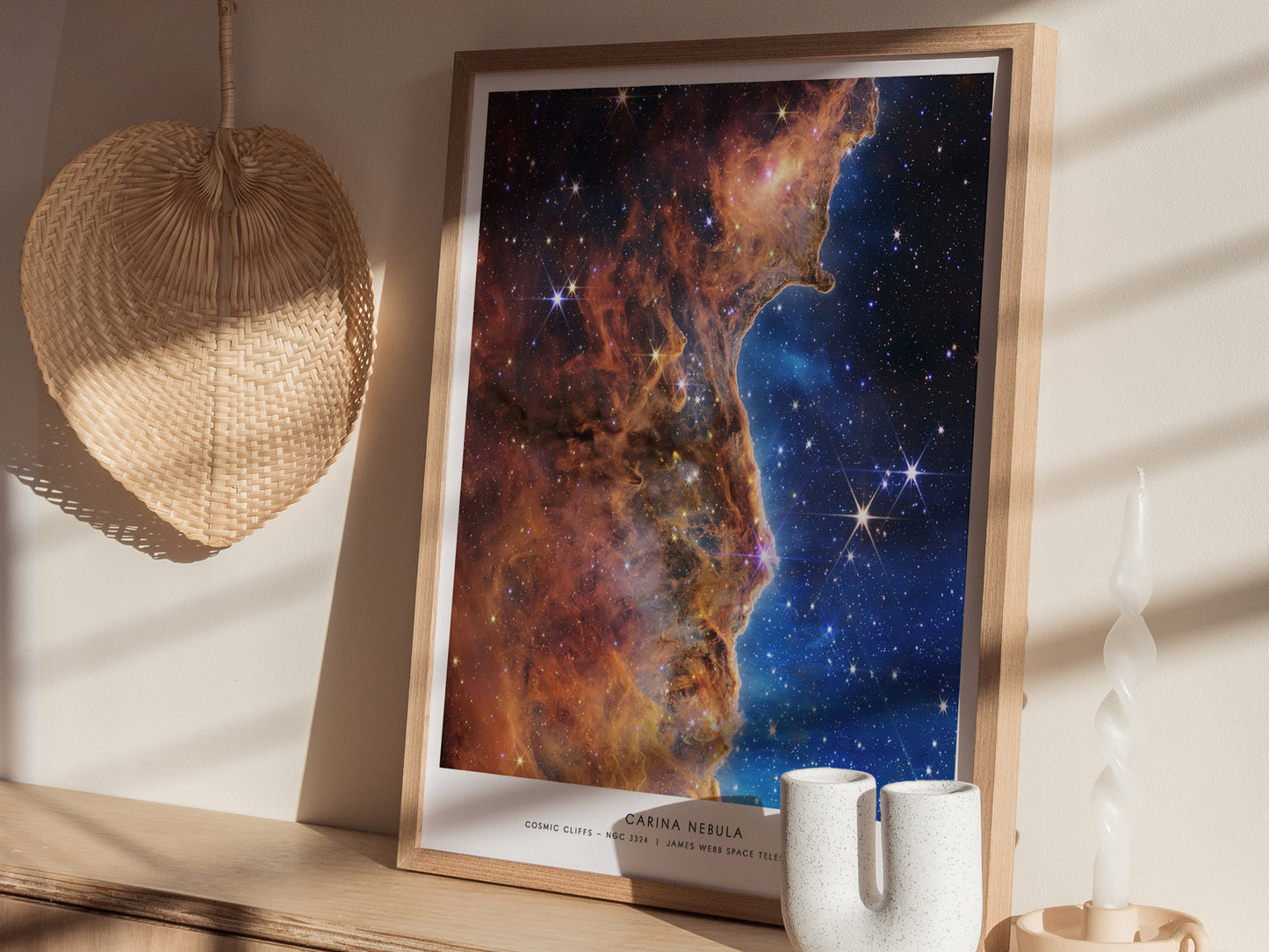 Natural wood frame Carina Nebula JWST print styled on a shelf with soft lighting