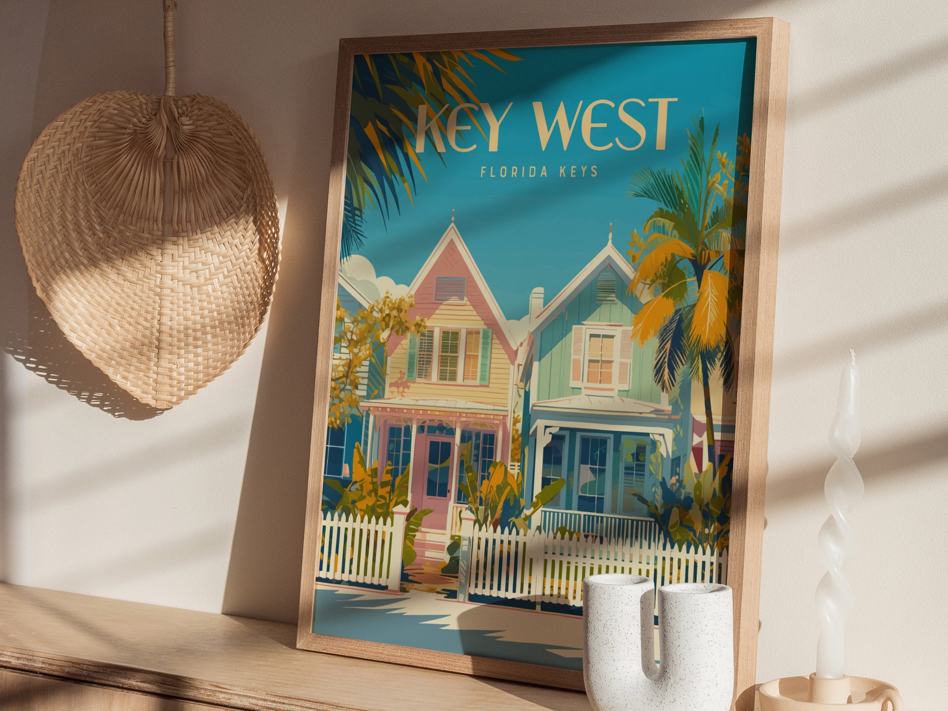 A framed Key West poster featuring colorful houses and palm trees is displayed on a wooden surface. Nearby, a woven basket.