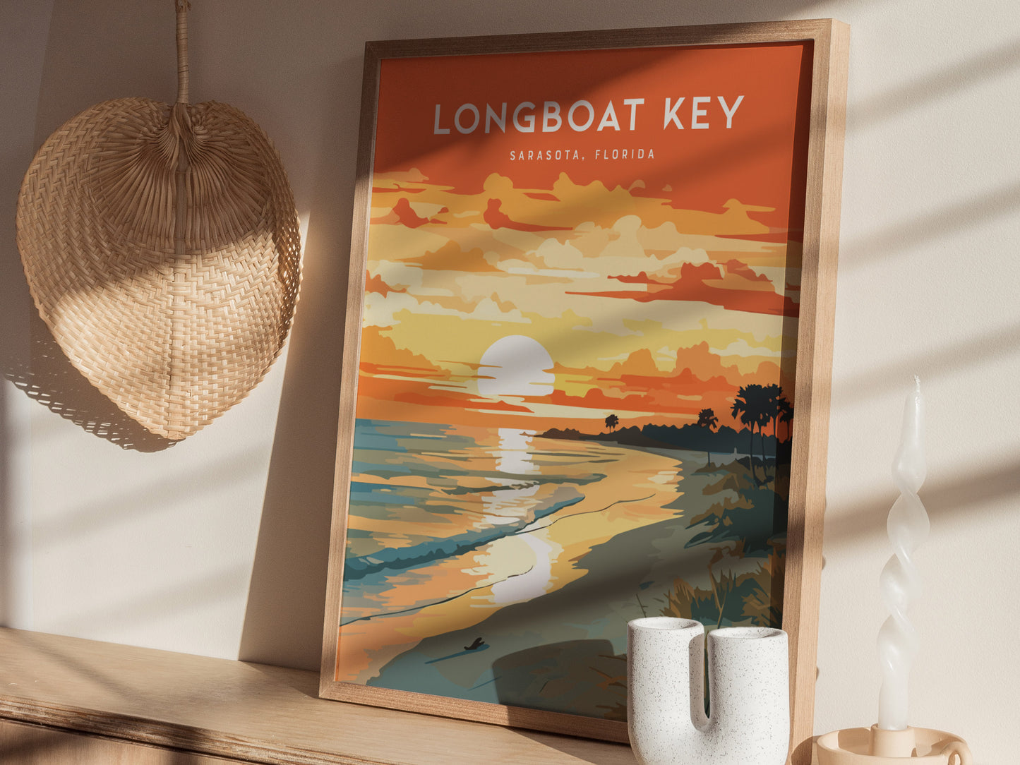 A framed poster titled Longboat Key, Sarasota Florida is displayed on a wooden shelf. The artwork features a vibrant beach sunset scene with palm trees and ocean waves.