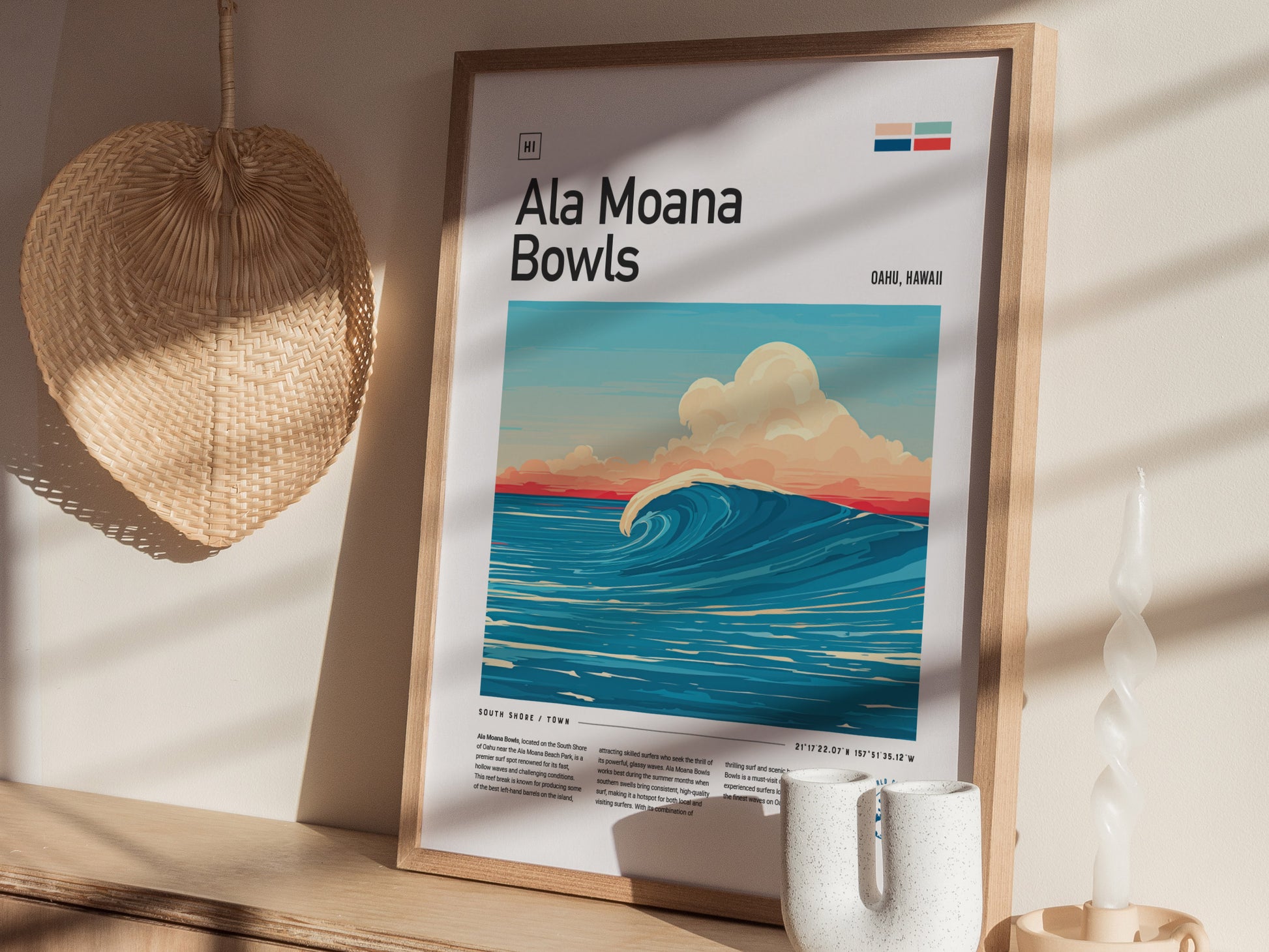 A framed Ala Moana Bowls surf poster features a vibrant ocean wave under a colorful sky. Its displayed on a wooden shelf beside a woven fan and a twisted candle.