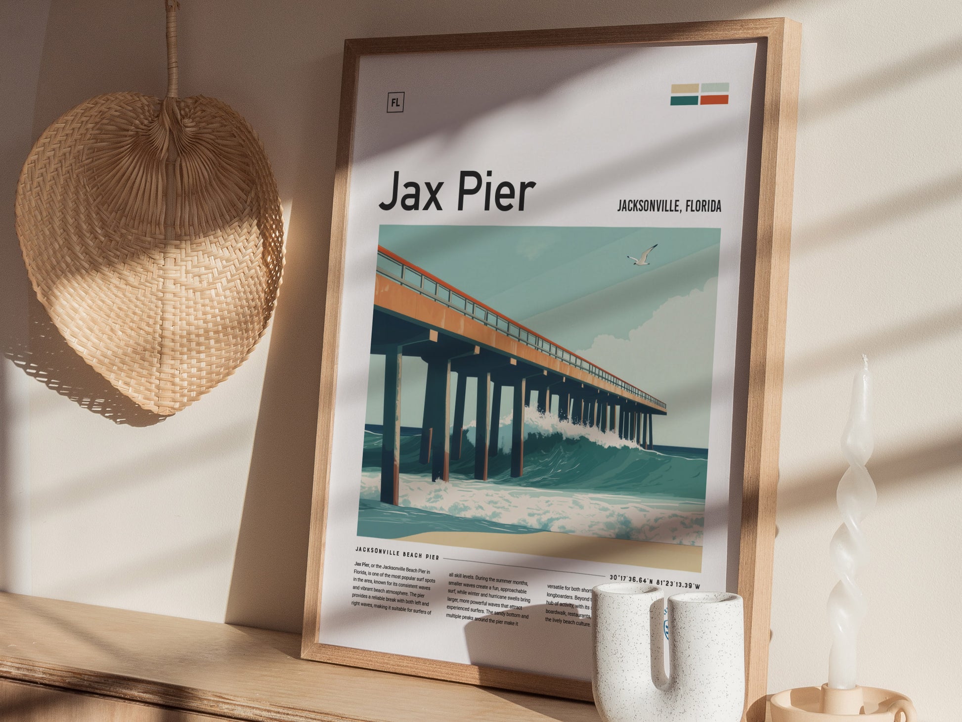A framed Jax Pier surf poster is displayed on a wooden surface, with a woven wall decoration and a twisted candle nearby. Sunlight casts shadows on the wall.