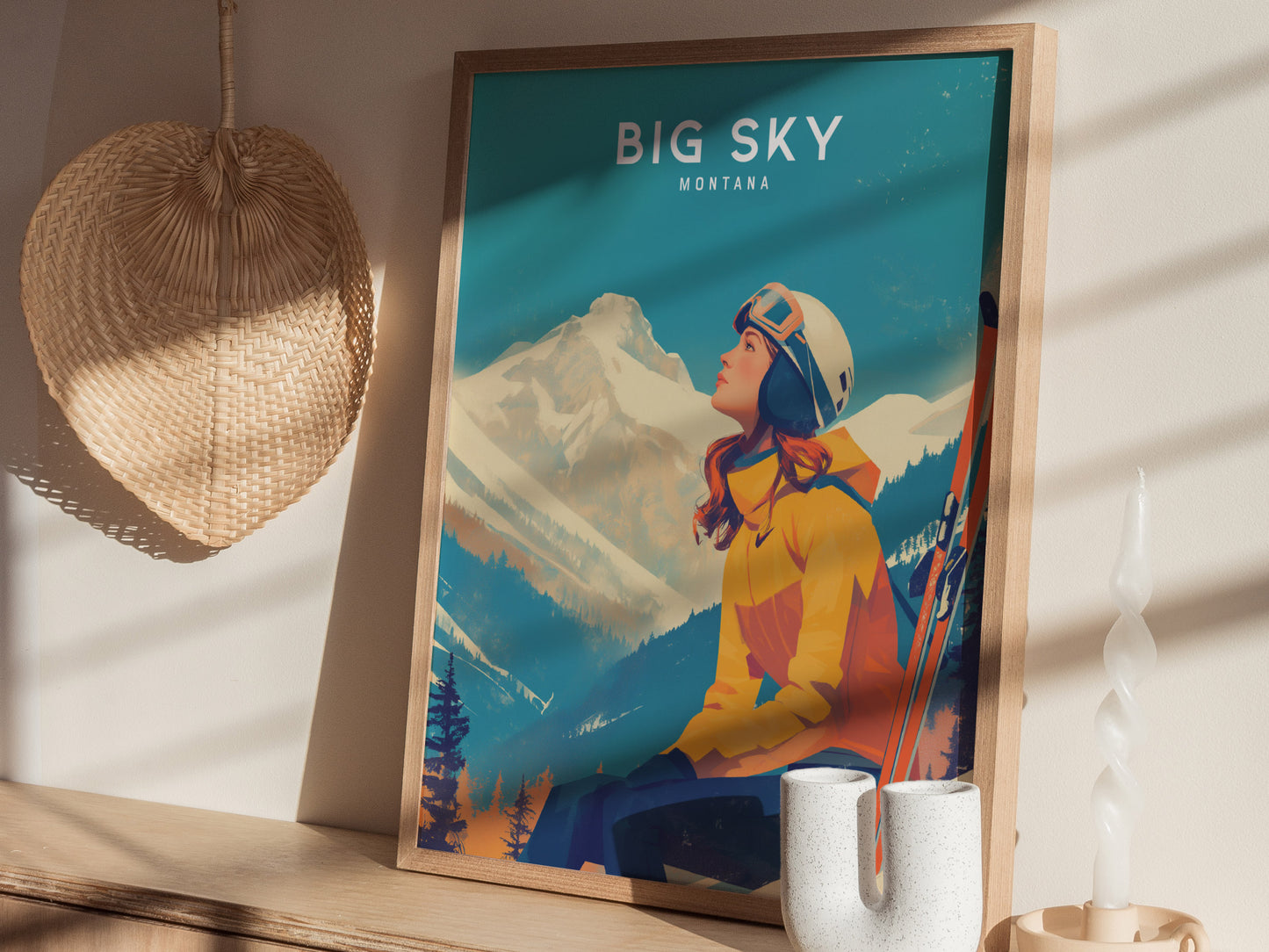 Framed artwork featuring a skier in a yellow jacket, gazing at snowy mountains under the title Big Sky Montana. Displayed on a wooden surface with decor items.